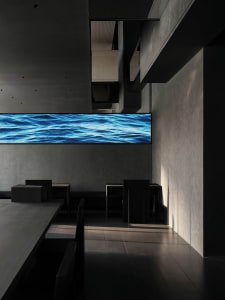 A calm restaurant with a large screen displaying a waterfall scene, surrounded by chairs and tables