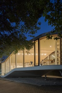 A modern dining and social space with concrete walls, multiple chairs, and dining tables, creating an inviting and comfortable atmosphere