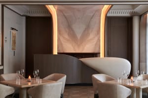 Modern restaurant interior with curved wall, grey and white tones, and wine glasses on tables