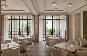 Sophisticated restaurant interior with white chairs and tables, potted plants, and varied chair styles