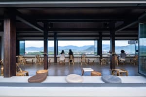 Outdoor dining area with wooden furniture, tables, and chairs, surrounded by a mountain landscape with a relaxed and inviting atmosphere