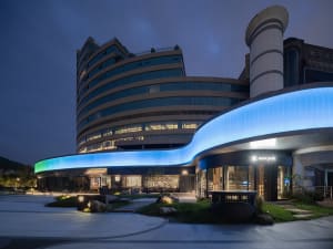 Modern building with a blue accent and windows lit from inside, creating a lively atmosphere at night