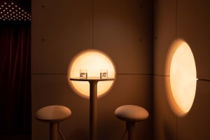 Cozy seating arrangement with two round tables and chairs, illuminated by circular lights creating a warm and inviting atmosphere