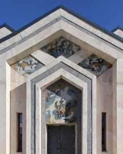 Ornate stone building with a grand archway, gray and white tones, and intricate designs on the walls