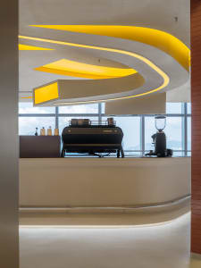 A modern coffee shop interior with two espresso machines, cups, and a bottle, set in a welcoming atmosphere