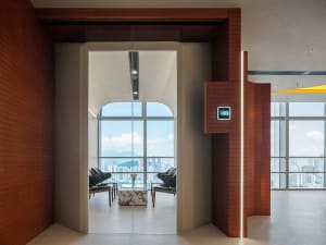 An open living area with a cozy seating arrangement, dining table, and natural light from a glass door leading to a balcony with a city skyline view