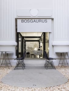A modern storefront display featuring chairs and tables, with a clean and bright appearance, likely made of white materials