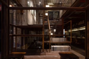 Cozy restaurant interior with a staircase, wooden railing, benches, and chairs, featuring a warm and inviting atmosphere