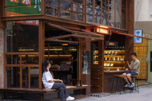 Cozy Asian restaurant with wooden floors and walls, featuring a dining area with tables, chairs, and various items, and a relaxed atmosphere with a focus on food and leisure