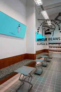 A modern coffee shop with brown and white walls, benches, and a large TV mounted on the wall, creating a warm and inviting atmosphere