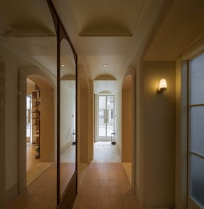 A modern hallway with a mirror and door, featuring a clean and modern look with tiled flooring and books placed along the space