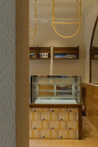 A cozy restaurant interior with a glass display case filled with food items, accompanied by books and an inviting atmosphere
