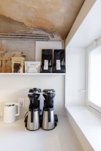 A well-stocked kitchen counter with coffee makers, cups, and coffee beans, creating a cozy atmosphere for enjoying a warm cup of coffee