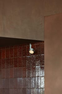 Warm bathroom with red brick walls, brown tile floor, and two overhead lights
