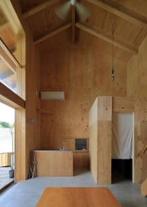 Open living area with wooden walls and ceiling, featuring two sinks, a refrigerator, and a potted plant, creating a warm and inviting atmosphere