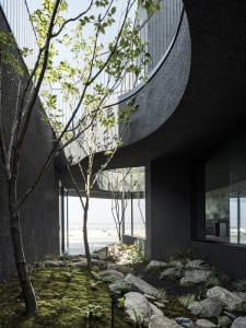 Modern house with a black exterior, spiral staircase, and a balcony on the second floor, surrounded by trees