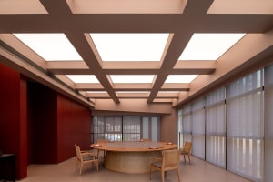 Modern dining room with a wooden dining table, red walls, and several chairs, exuding warmth and sophistication