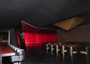 Modern restaurant interior with red walls, black tables, and chairs in a stylish dining area