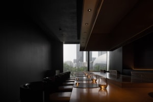 Elegant dining space with a long wooden table, chairs, and wine glasses, set for a dinner event