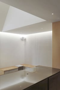 Empty minimalist kitchen with white walls, a wooden countertop, and two benches on either side