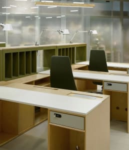 Office space with multiple wood desks and green cushioned chairs, designed for productivity and collaboration