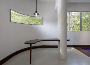 Clean and minimalistic interior space with a central column, white walls, and natural light from two windows