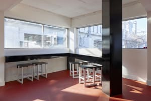 A clean and inviting restaurant interior with a long dining table surrounded by multiple wooden chairs, ready for guests to dine