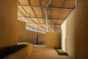 A modern building with a yellow exterior, featuring a large open area with a high ceiling, concrete walls, and ample natural light