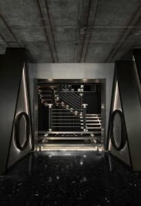 A hotel staircase with metal stairs, illuminated by lights on both sides, creating a sense of elegance and sophistication