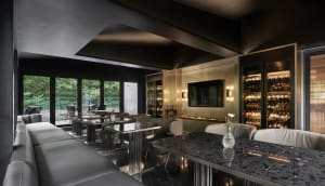Sophisticated living space with a black marble table, chairs, and a mounted TV, surrounded by wine glasses