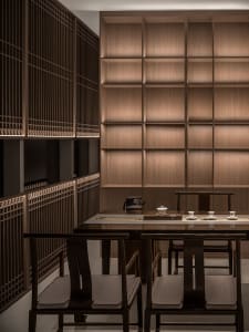 A cozy dining area with a wooden table and chairs, surrounded by cups, suggesting a warm and inviting atmosphere