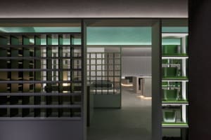 Modern kitchen with white walls, green accents, and a functional layout featuring a sink, oven, and refrigerator, with scattered bottles adding a personal touch
