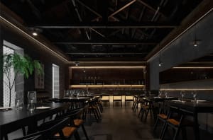 Elegant restaurant interior with a long dining table, wooden floors, stone walls, and formal table settings