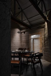 A warm and inviting dining area with a wooden table, stone walls, and wine glasses, suggesting a space for social gatherings
