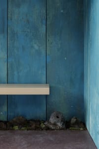 A simple wooden bench against a blue wall in a serene and calm rustic setting
