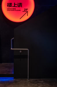 Modern interior design featuring a black wall with a red circle, two staircases, and a sleek atmosphere