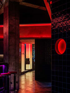 Dark interior space with a red glow, two chairs, and a doorway leading to another area