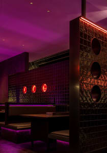 Modern restaurant interior with a purple accent wall, black tile flooring, and unique red circle designs on the walls