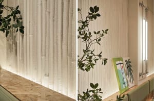 A cozy indoor space with a white tile wall, a potted plant, and a painting, creating a warm ambiance