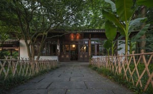 Serene Asian courtyard with a wooden fence, a large doorway, and chairs placed around the area