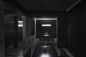 Dark restaurant interior with tables, chairs, and cups, featuring a moody atmosphere