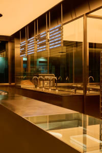 Industrial kitchen with stainless steel counters, multiple sinks, and bottles on countertops, conveying a clean and organized atmosphere