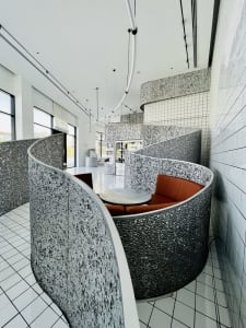 A modern living space with a dining table, chairs, patterned walls, and potted plants, creating a comfortable and inviting atmosphere