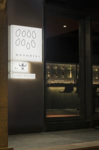 A restaurant interior with a wooden bar, bottles, and two chairs in a sophisticated atmosphere