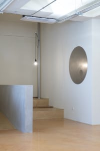 Interior space with a staircase, wooden steps, and a metal pipe along the wall, in a dark atmosphere