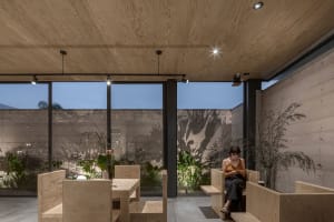 Cozy restaurant space with wooden paneling, potted plants, and comfortable seating areas