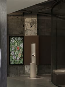 A modern interior space with a white pillar in the center, featuring two posters on the wall with a minimalist design