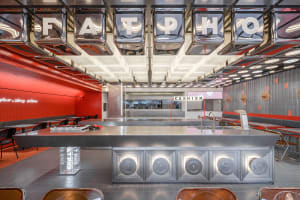 Industrial-style cafe with a counter, dining tables, chairs, and appliances, set in a clean and well-organized space