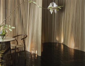 A modern dining space with a wooden table and chairs, surrounded by bamboo panelled walls in a black and white theme