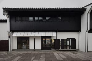 Old building with a black exterior, white roof, and large window, featuring a glass door and traditional architectural style
